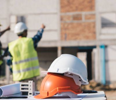 Structural engineer and architect working with blueprints discuss at the outdoors construction site.